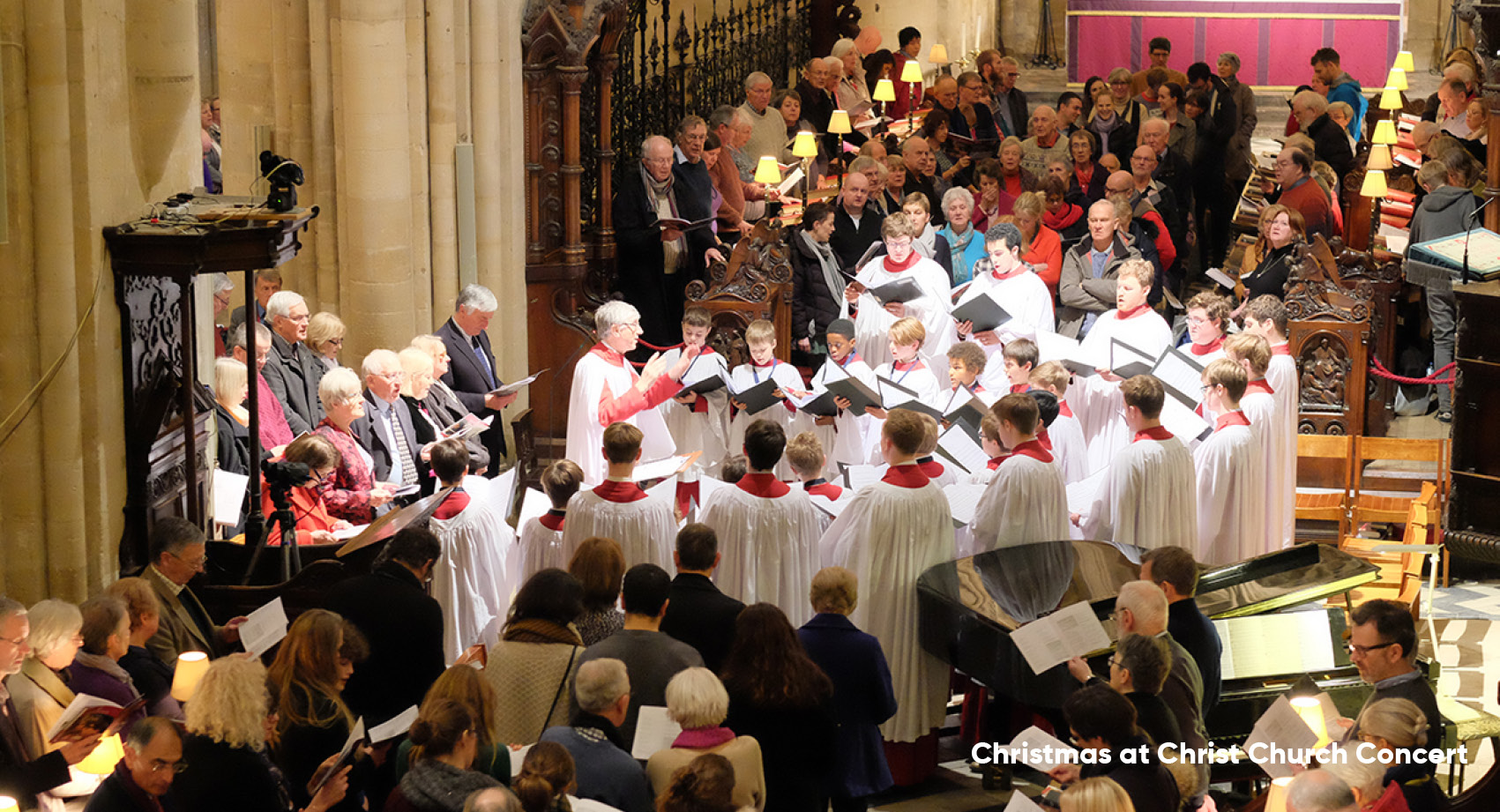 Christ Church Cathedral Choir in white robes singing in the cathedral with audience members