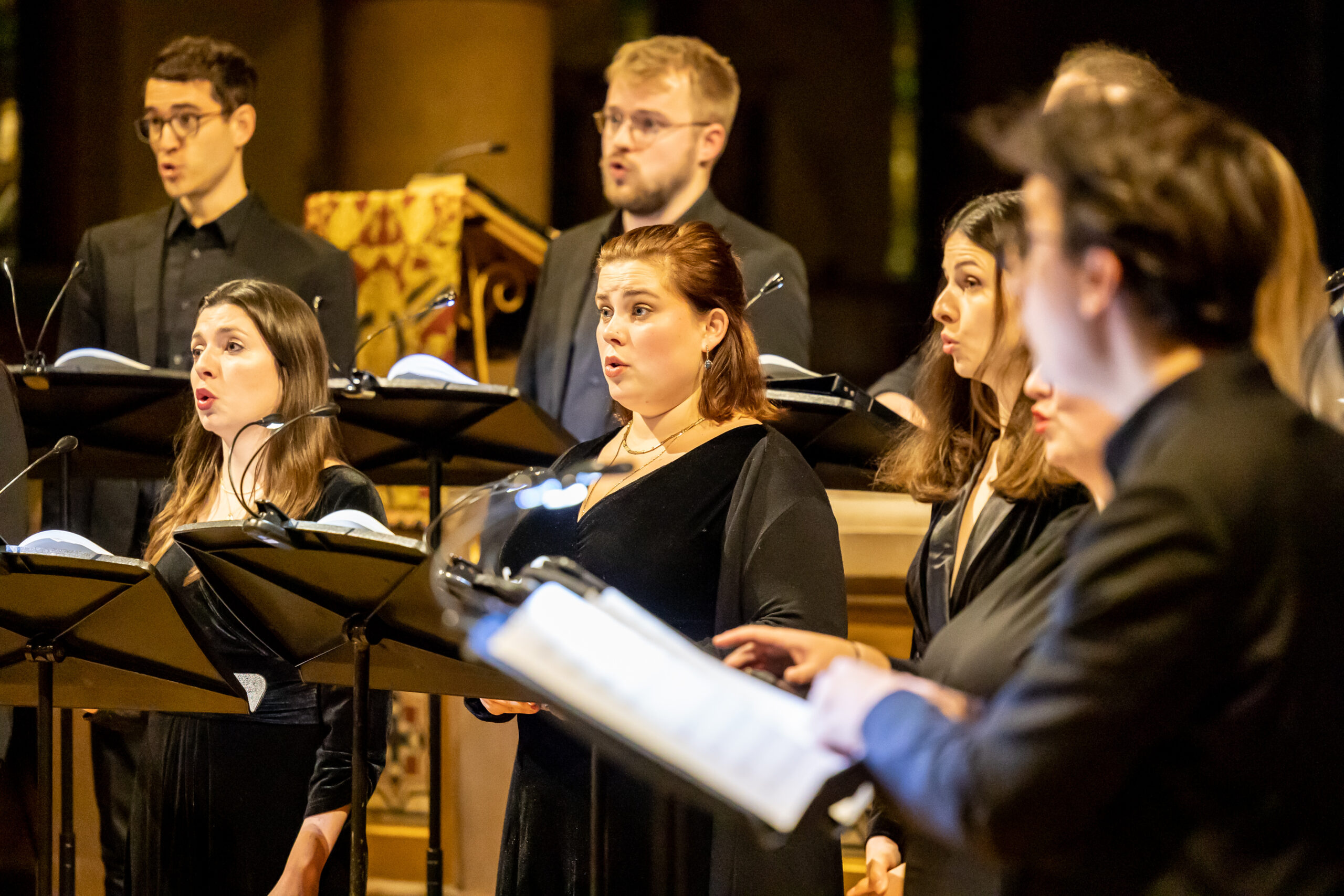 A close up of a choir with music on stands perform