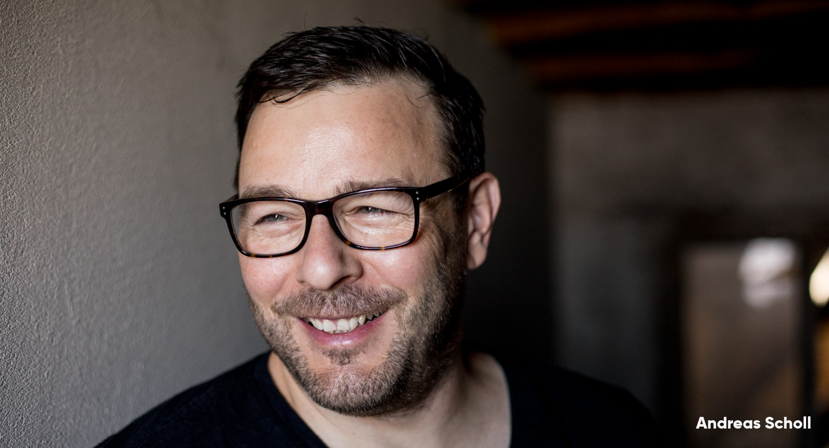 A headshot of Andreas Scholl smiling wearing black top.