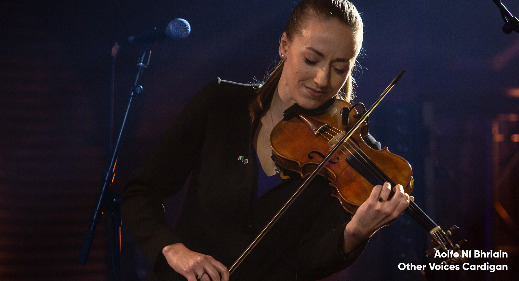 Aoife Ní Bhriain playing the violin with a microphone to her left