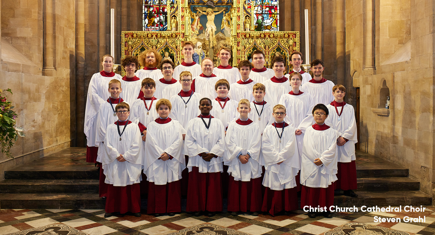 The Choir of Christ Church Cathedral standing in a group in their cassocks in front of the Christ Church Cathedral alter